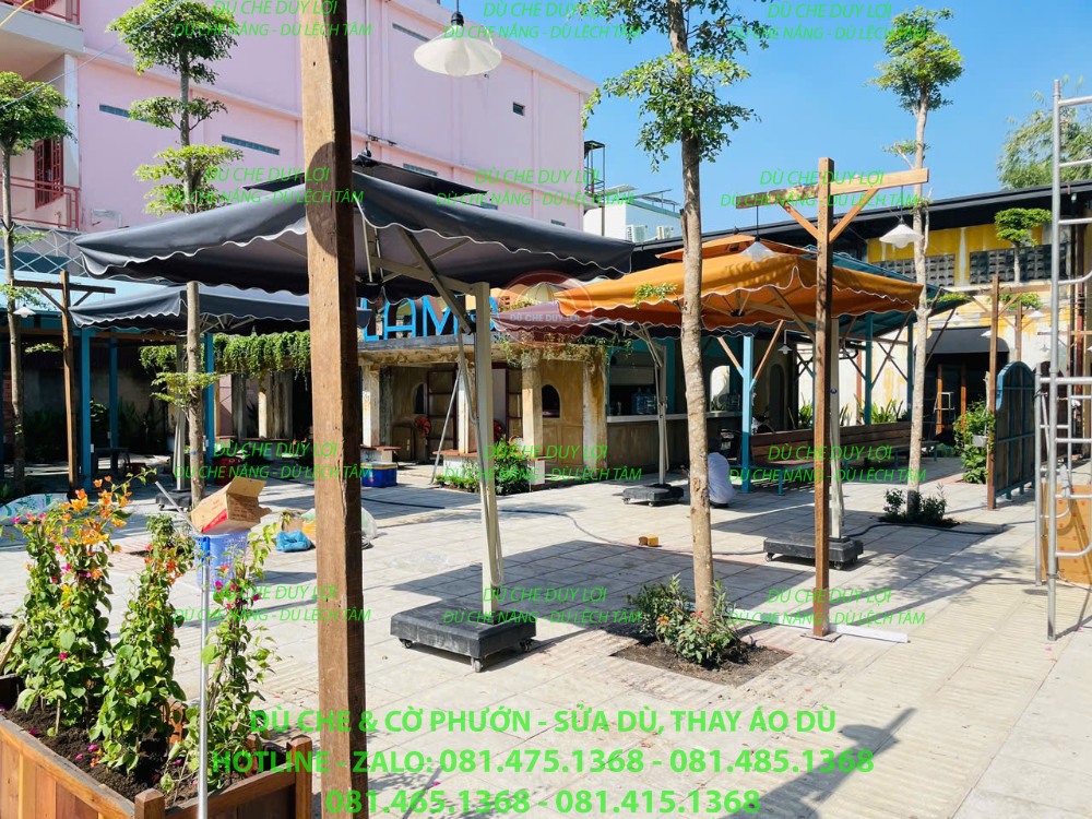 Dù lệch tâm vuông màu sẫm bố trí cạnh lối đi trong khu cafe ngoài trời.