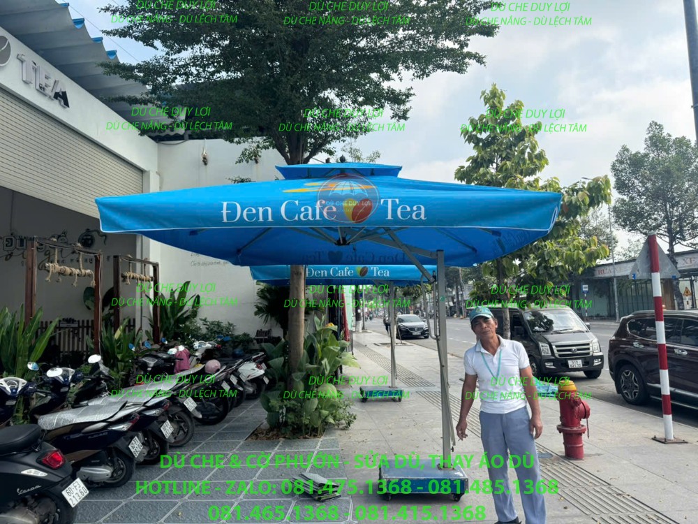 Dù lệch tâm vuông màu xanh in Đen Cafe & Tea đặt phía trước quán.