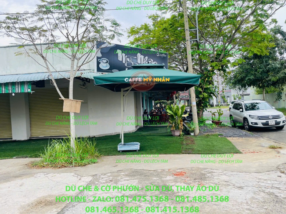 Dù tròn đúng tâm màu xanh in thương hiệu đặt trước quán cafe.